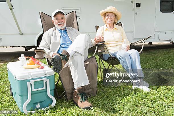 senior couple sit outside rv home - folding chair stock-fotos und bilder