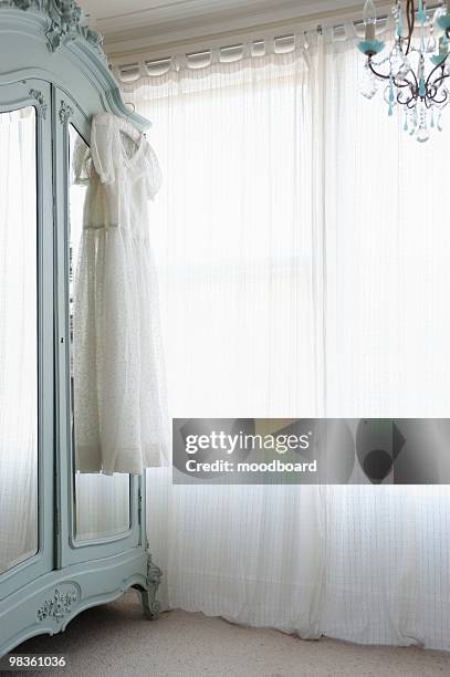 christening gown on wardrobe at window with net curtains - christening gown stock pictures, royalty-free photos & images