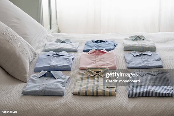 clean shirts ordered on a bed - obsession photos et images de collection