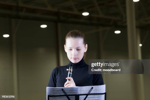 clarinet player stands with sheet music under spotlights - soloist stock pictures, royalty-free photos & images