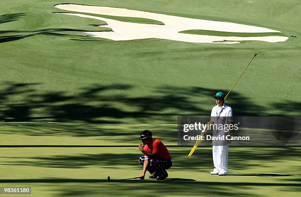 Ryo Ishikawa of Japan lines up his putt on the tenth hole with the help of his caddie Hiroyuki Kato during the second round of the 2010 Masters...