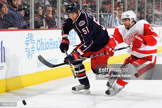 Fedor Tyutin of the Columbus Blue Jackets and Patrick Eaves of the Detroit Red Wings battle for control of a loose puck during the first period on...