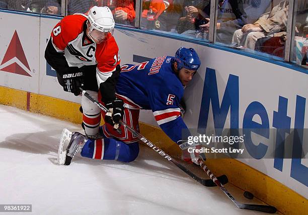 Dan Girardi of the New York Rangers reaches for the puck along the boards under pressure by Mike Richards of the Philadelphia Flyers in the first...