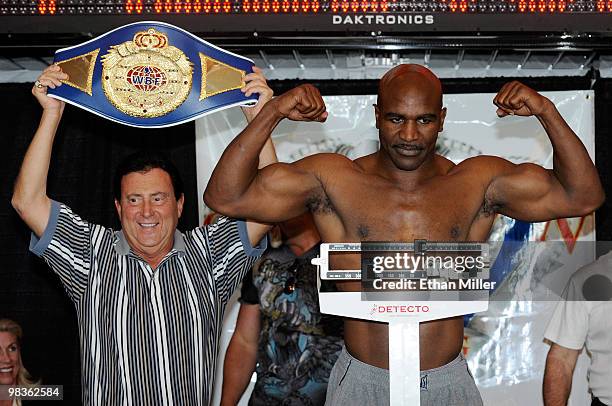 Boxer Evander Holyfield poses on the scale next to Crown Boxing matchmaker Frank Luca during the official weigh-in for Holyfield's bout against...