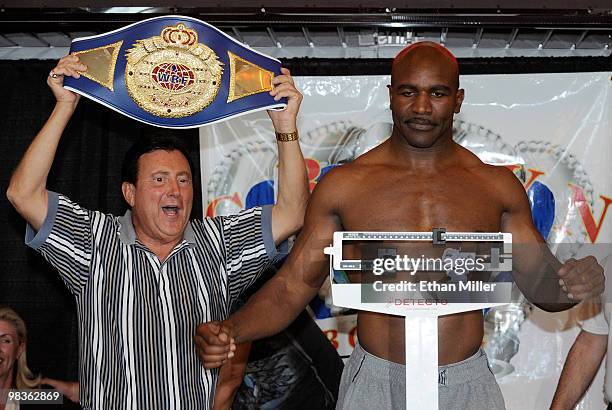 Boxer Evander Holyfield poses on the scale next to Crown Boxing matchmaker Frank Luca during the official weigh-in for Holyfield's bout against...