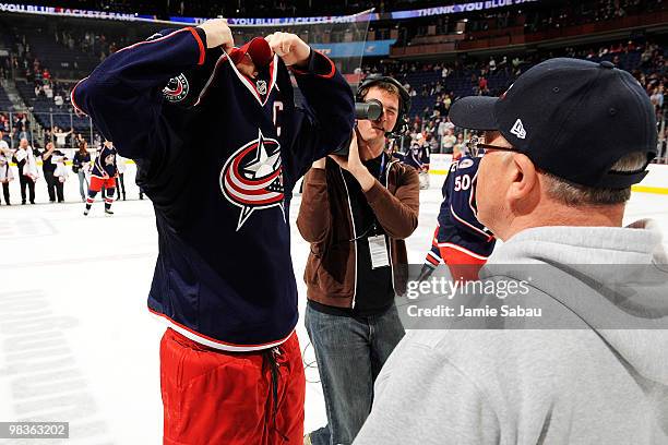 Rick Nash of the Columbus Blue Jackets removes his jersey and gives it to a fan after their game against the Detroit Red Wings during fan...