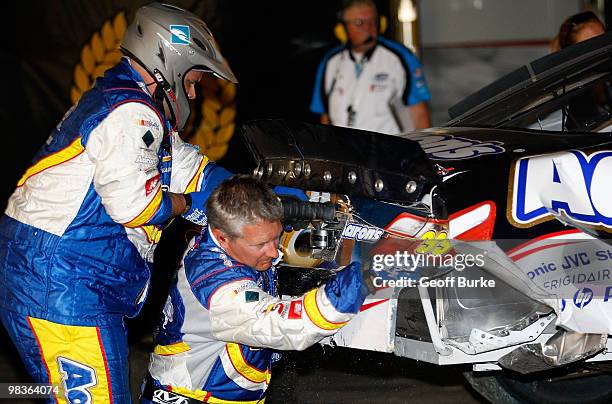 Crew members cut away damage from the Aaron's Dream Machine Toyota in the garage after a crash during the NASCAR Nationwide Series Bashas'...