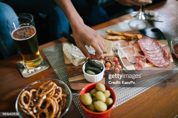 indulging in a charcuterie at a house party - tabla de cortar fotografías e imágenes de stock