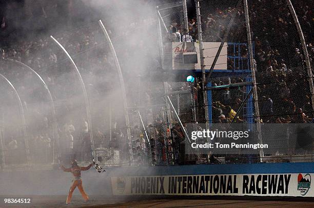 Kyle Busch, driver of the Combos Toyota, celebrates by grabbing the flag after winning the NASCAR Nationwide Series Bashas' Supermarkets 200 at...