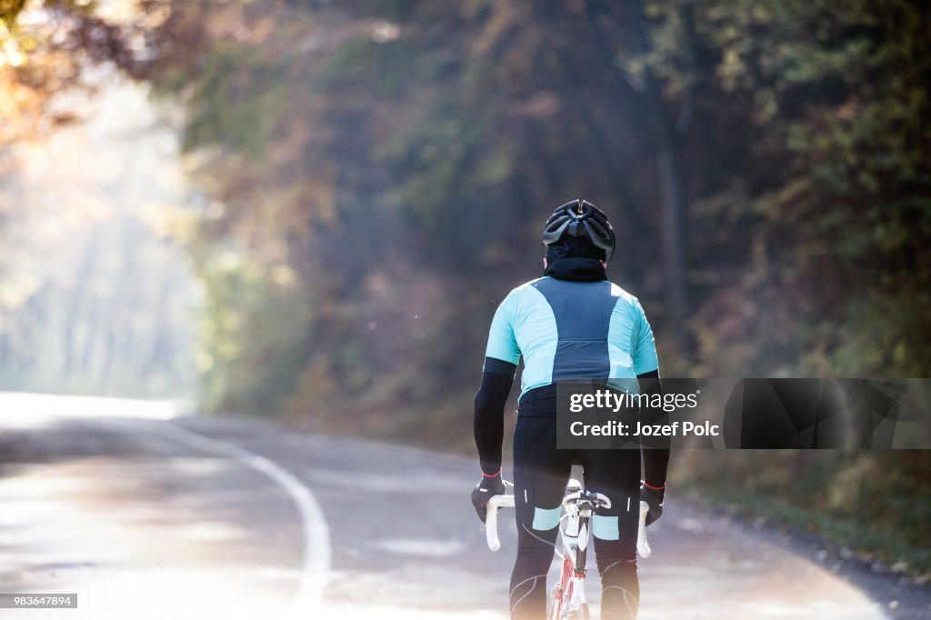 Young sportsman riding his bicycle outside in sunny autumn natur