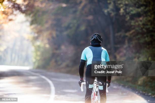 young sportsman riding his bicycle outside in sunny autumn natur - natuur stock pictures, royalty-free photos & images