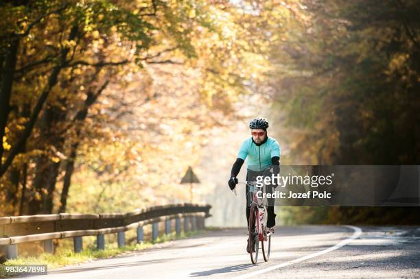 young sportsman riding his bicycle outside in sunny autumn natur - natuur stock pictures, royalty-free photos & images