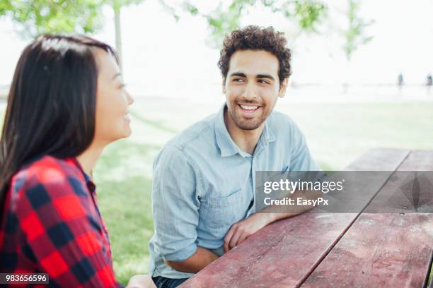 young couple sitting and talking at picnic table - en la cima del mundo fotografías e imágenes de stock