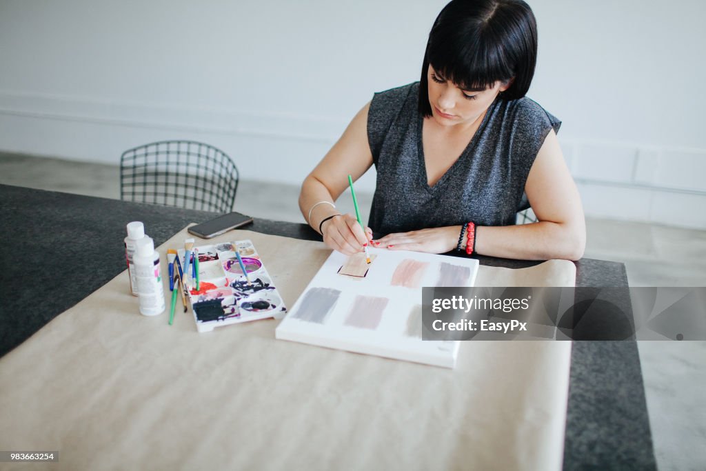 Female artist painting at a work station