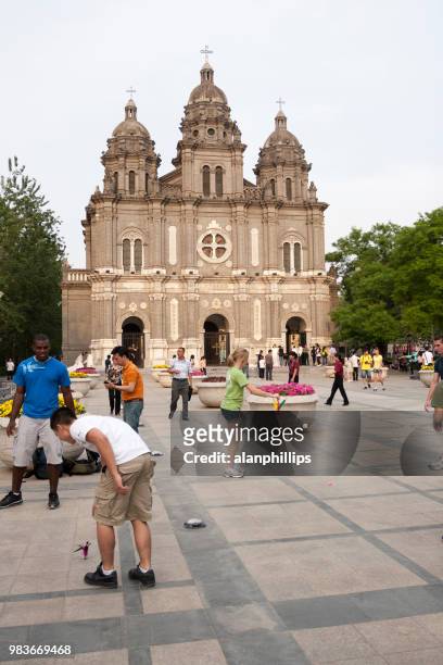 若者は、王府井、北京、中国の聖ジョセフ教会の前で演奏します。 - 東城 ストックフォトと画像