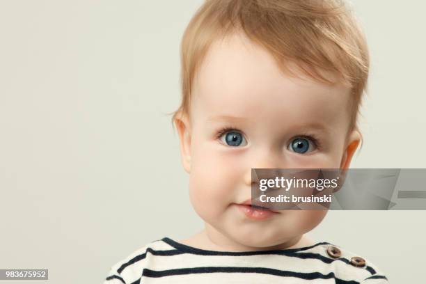 close-up portret van jongetje 9 maanden oud in studio op blauwe achtergrond - jongensbaby's stockfoto's en -beelden