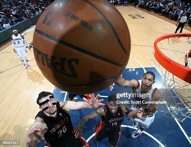 Al Horford of the Atlanta Hawks battles for a rebound against Hedo Turkoglu and Amir Johnson of the Toronto Raptors on April 9, 2010 at Philips Arena...