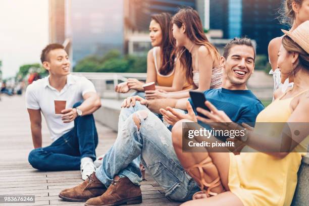 multi-ethnic group of boys and girls flirting outdoors - sitting on ground stock pictures, royalty-free photos & images