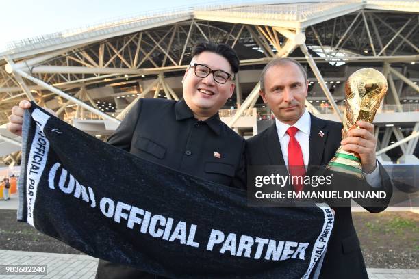 Impersonators of Russian President Vladimir Putin and North Korean leader Kim Jong Un pose with a replica of the World Cup trophy at the end of the...