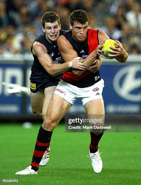 Bryce Gibbs of the Blues tackles David Hille of the Bombers during the round three AFL match between the Carlton Blues and the Essendon Bombers at...