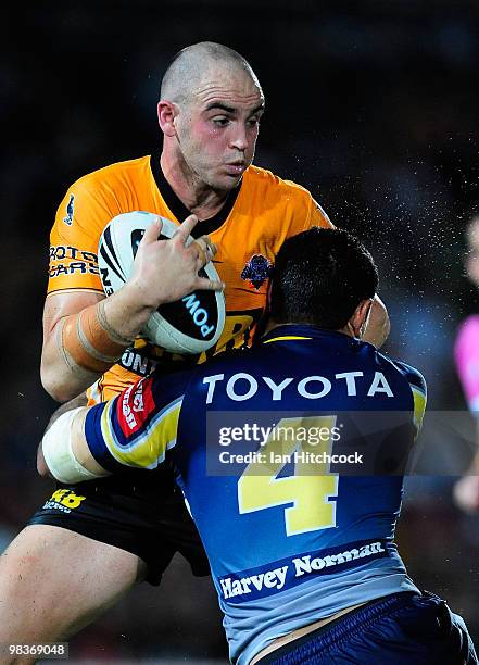 Liam Fulton of the Tigers is tackled by Willie Tonga of the Cowboys during the round five NRL match between the North Queensland Cowboys and the West...