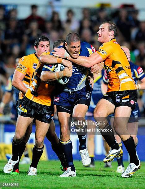 Willie Mason of the Cowboys is tackled by Robbie Farrar and Gareth Ellis of the Tigers during the round five NRL match between the North Queensland...