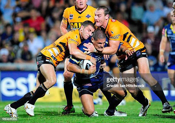 Willie Mason of the Cowboys is tackled by Robbie Farrar and Gareth Ellis of the Tigers during the round five NRL match between the North Queensland...