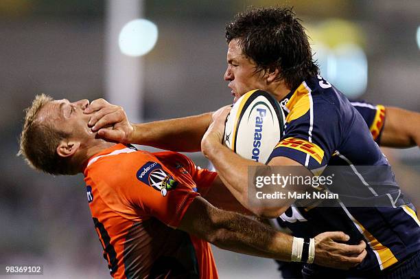 Adam Ashley-Cooper of the Brumbies palms off Sarel Pretorius of the Cheetahs during the round nine Super 14 match between the Brumbies and the...