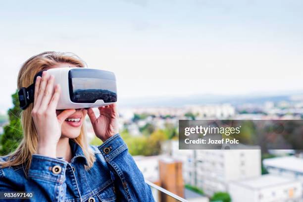 woman wearing virtual reality goggles standing on a balcony - office game stock pictures, royalty-free photos & images