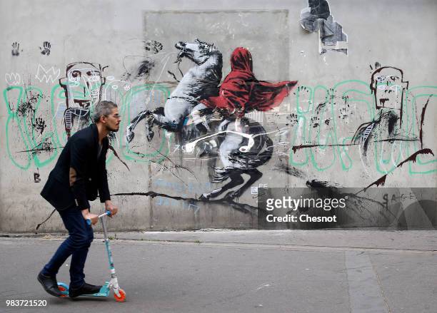 Man walks past a recent artwork attributed to street artist Banksy on June 25, 2018 in Paris, France. Six frescoes, attributed to Banksy, were...
