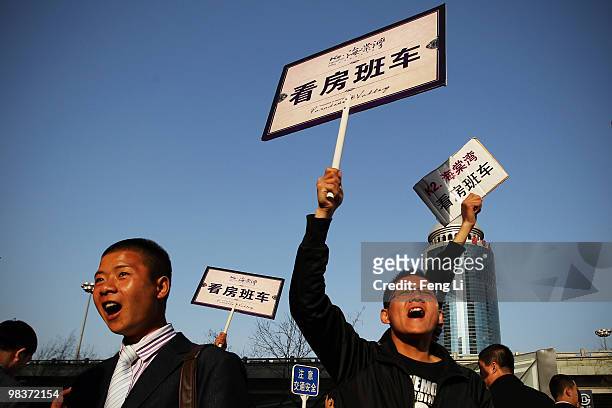 Sales people lift signs to promote real estate sales at the 2010 Beijing Spring Real Estate Trade Fair on April 10, 2010 in Beijing, China. Since the...