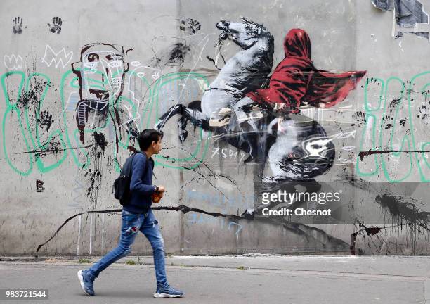 Young person walks past a recent artwork attributed to street artist Banksy on June 25, 2018 in Paris, France. Six frescoes, attributed to Banksy,...