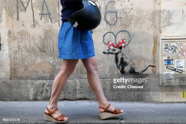 Woman walks past a recent artwork attributed to street artist Banksy on June 25, 2018 in Paris, France. Six frescoes, attributed to Banksy, were...