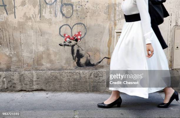 Woman walks past a recent artwork attributed to street artist Banksy on June 25, 2018 in Paris, France. Six frescoes, attributed to Banksy, were...