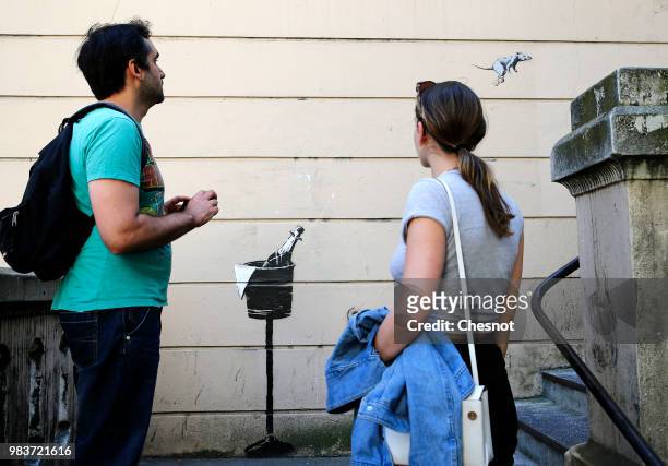 People are watching a recent artwork attributed to street artist Banksy on June 25, 2018 in Paris, France. Six frescoes, attributed to Banksy, were...
