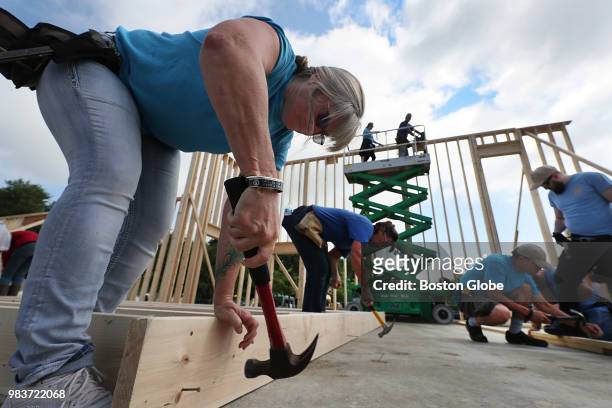 Volunteer Diane Allan, from Arizona, hammers nails into a section of wall as volunteers help to build the new Chinese Bible Church of Greater Lowell...