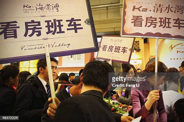 Sales people lift signs to promote real estate sales at the 2010 Beijing Spring Real Estate Trade Fair on April 10, 2010 in Beijing, China. Since the...