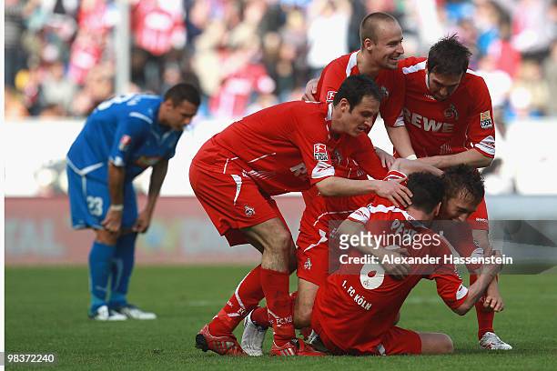 Adam Matuschyk of Koeln celebrates scoring his second team goal with his team mates whilst Sejad Salihovic of Hoffenheim looks dejected during the...