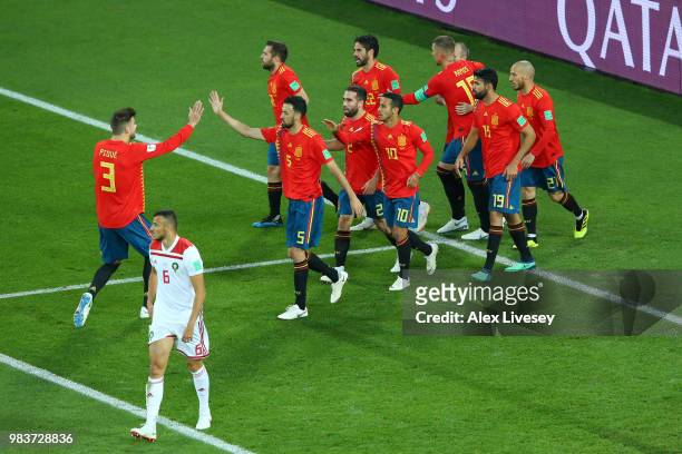 Isco of Spain is congratulated by teammates after scoring his sides opening goal to make the score 1-1 as Romain Saiss of Morocco walks off dejected...