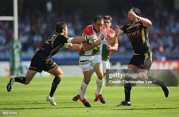 Julien Peyrelongue of Biarritz is tackled by James Hook and Mike Phillips of Ospreys during the Heineken Cup Quarter Final match between Biarritz...