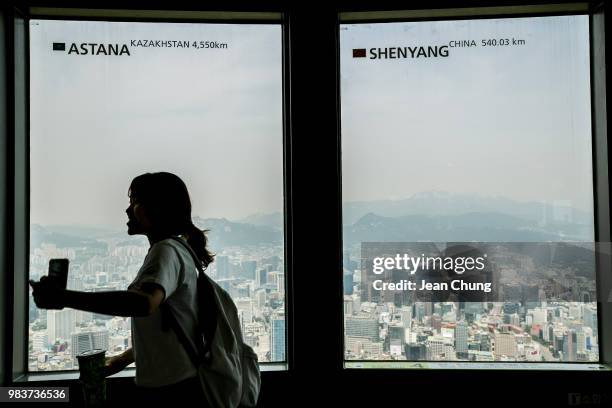 Tourist walk in front of the window where the aerial view of downtown Seoul is observed on Seoul N Tower, on June 25, 2018 in SEOUL, South Korea....