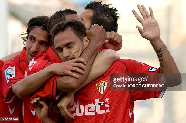 Sevilla's defender Lolo celebrates with teammates after scoring against Malaga during a Spanish league football match at the Rosaleda stadium in...