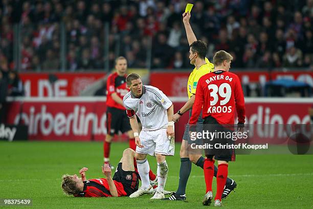 Referee Knut Kircher shows the yellow card to Bastian Schweinsteiger of Bayern after attacking Stefan Kiessling of Leverkusen during the Bundesliga...