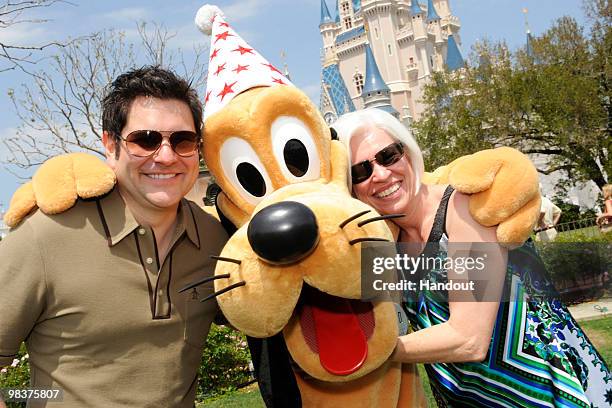 In this handout photo provided by Disney, Jay DeMarcus of the country music trio "Rascal Flatts," and his mother Caron Myers pose with Pluto in front...