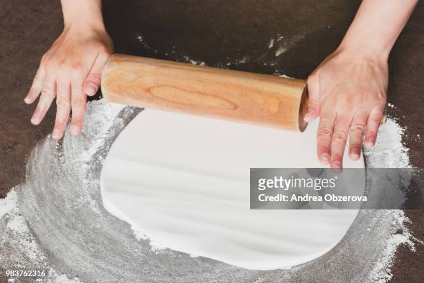woman using rolling pin preparing royal icing for cake decorating, hands detail - rolling pin stock-fotos und bilder