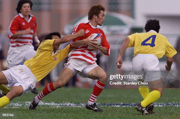 Tomokazu Yamauchi of Japan is checked by the Thai defence in the Bowl competition during the final day of the World Rugby Sevens Series, Malaysia...