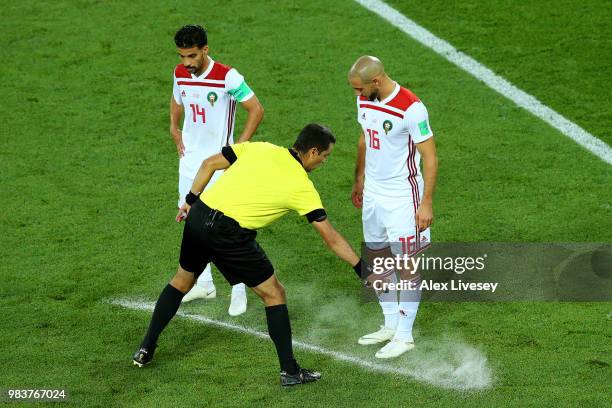 Referee Ravshan Irmatov uses vanishing spray to mark where the Morocco wall should stand for a free kick during the 2018 FIFA World Cup Russia group...