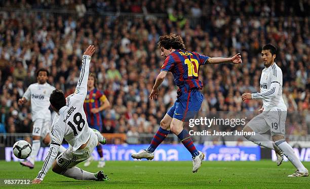 Lionel Messi of FC Barcelona scores his sides opening goal in between Raul Albiol and Ezequiel Garay of Real Madrid during the La Liga match between...