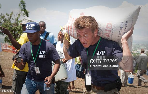 Actor Sean Penn carries belongings of a shelter camp resident as they are prepared to be relocated to a new camp April 10, 2010 in Petionville,...