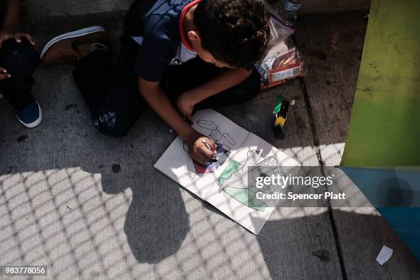 Honduran child works in a coloring book while waiting with his family along the border bridge after being denied entry from Mexico into the U.S. On...